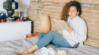 Ilustrasi membaca di tempat tidur. (Photo by Nataliya Vaitkevich: https://www.pexels.com/photo/cozy-woman-in-white-sweater-and-blue-denim-jeans-reading-a-book-5426077/)