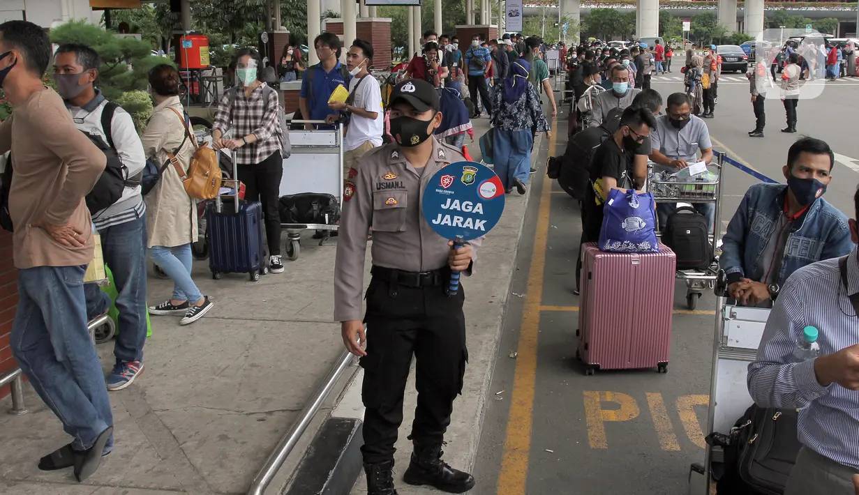 Polisi mengingatkan jaga jarak saat calon penumpang mengntre untuk rapid test antigen di Terminal 2 Bandara Soekarno-Hatta, Tangerang, Banten, Selasa (22/12/2020). Layanan rapid test antigen dibanderol dengan harga Rp 200 ribu. (merdeka.com/Arie Basuki)