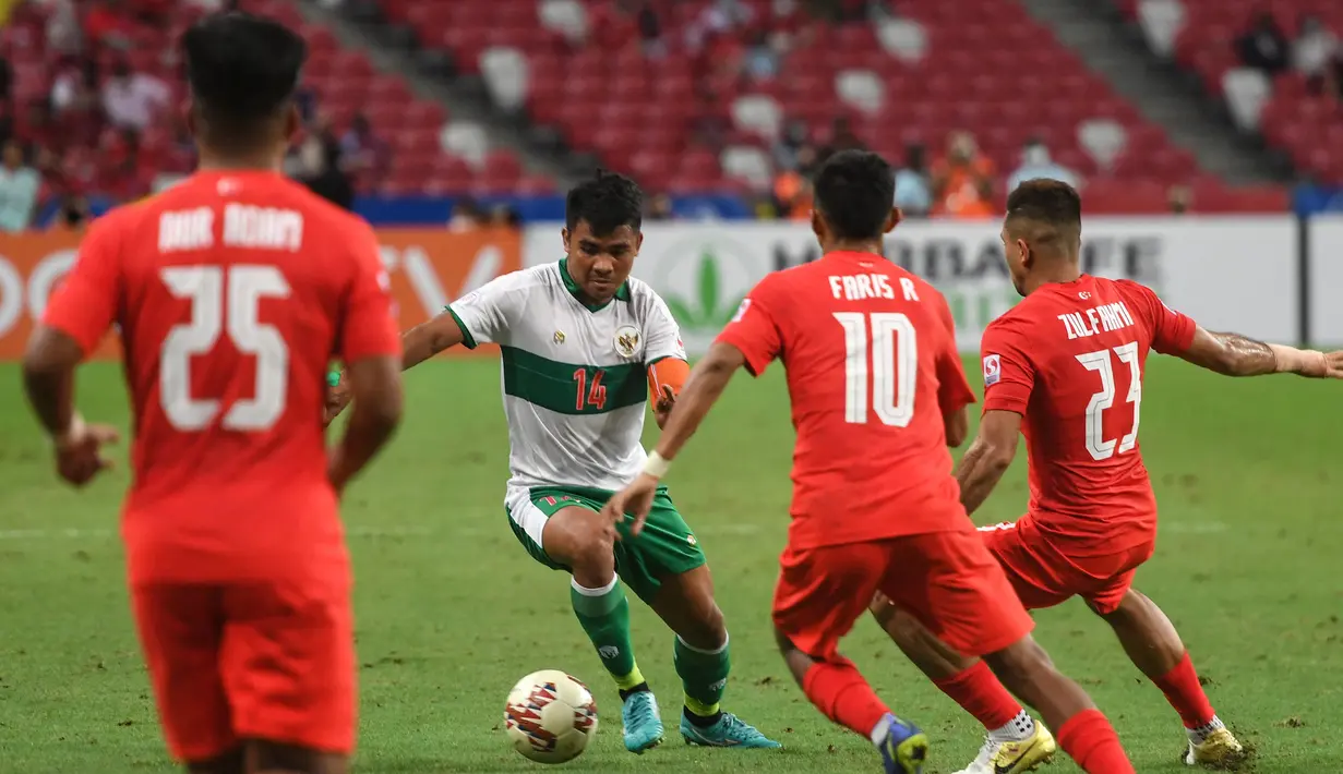 Pemain Indonesia Asnawi Mangkualam Bahar (kedua kiri) menggiring bola melewati para pemain Singapura pada pertandingan leg pertama semifinal Piala AFF 2020 di National Stadium, Singapura, Rabu (22/12/2021). Pertandingan berakhir imbang 1-1. (Roslan RAHMAN/AFP)