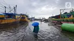 Nelayan melintasi banjir rob saat cuaca ekstrem di Pelabuhan Muara Baru, Penjaringan, Jakarta Utara, Rabu (28/12/2022). Banjir ROB, hujan deras dan  cuaca buruk melanda kawasan Pelabuhan Muara Baru saat siang menjelang sore hari. (Liputan6.com/Johan Tallo)