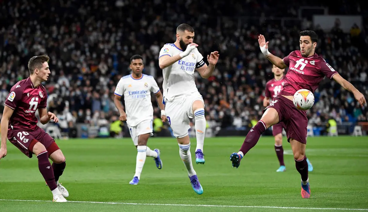 Pemain Real Madrid Karim Benzema (tengah) berebut bola dengan pemain Real Sociedad Jon Pacheco (kiri) dan Mikel Merino (kanan) pada pertandingan sepak bola Liga Spanyol di Stadion Santiago Bernabeu, Madrid, Spanyol, 5 Maret 2022. Real Madrid menang 4-1. (PIERRE-PHILIPPE MARCOU/AFP)