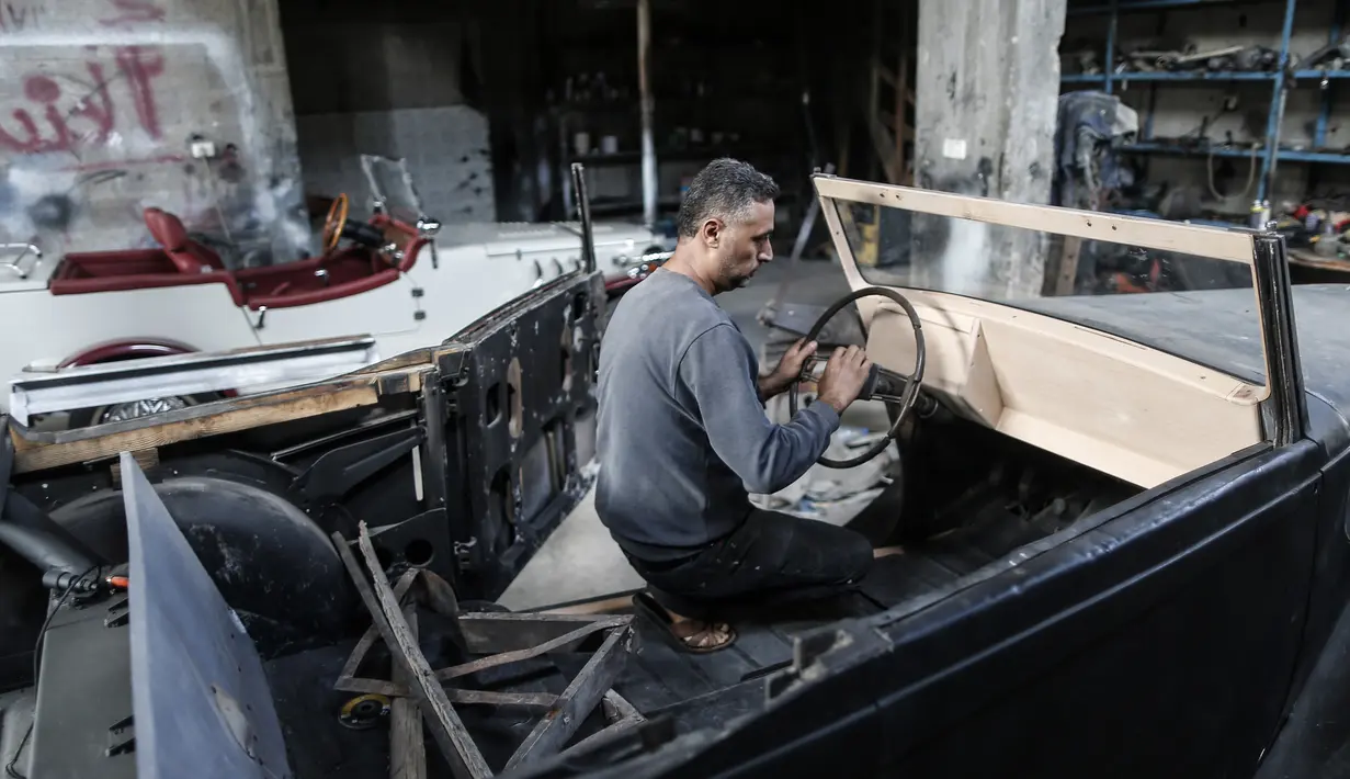 Munir Shindy memasang stir mobil tua di bengkelnya di Kota Gaza (28/10/2019).  Shindi berharap dapat berkendara sambil memamerkan mobilnya namun dia tahu hal itu tidak mungkin dilakukan akibat blokade Israel di Gaza. (AFP Photo/Mahmud Hams)