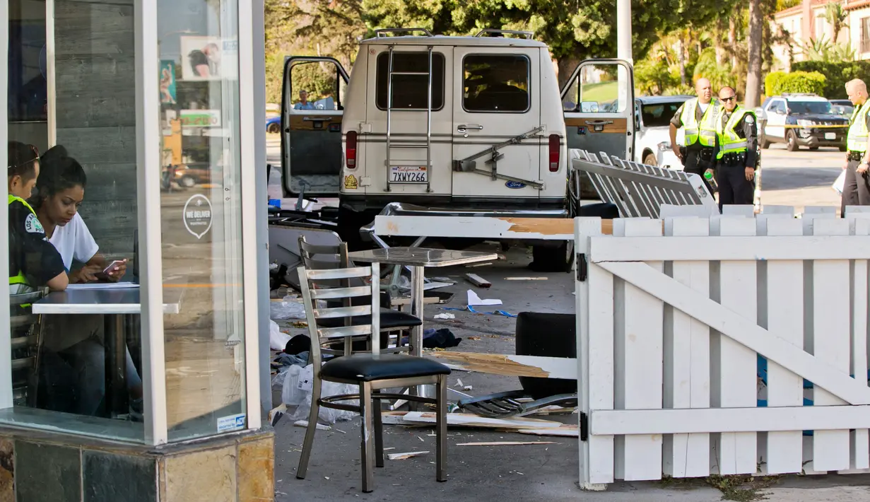 Penyidik kepolisian mewawancarai saksi mata setelah mobil van yang menabrak kerumunan orang di depan sebuah restoran di Los Angeles, Minggu (30/7). Sopir kendaraan itu telah ditangkap dan dibawa ke rumah sakit untuk diperiksa (AP Photo/Damian Dovarganes)
