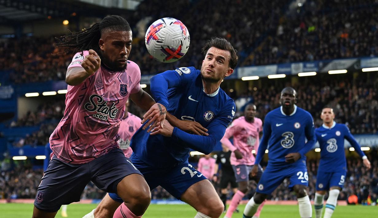 Pemain Everton, Alex Iwobi (kiri) berebut bola dengan pemain Chelsea, Ben Chilwell pada laga pekan ke-28 Liga Inggris 2022/2023 di Stamford Bridge, London, Minggu (19/03/2023) WIB. Laga berakhir dengan skor imbang 2-2. (AFP/Glyn Kirk)