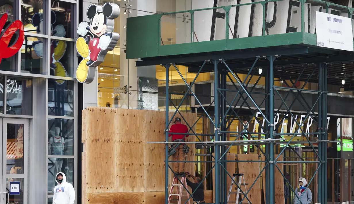 Pekerja memasang papan pelindung pada sebuah toko di Times Square di New York, Amerika Serikat,pada 1 November 2020. Langkah tersebut dilakukan saat para peretail berupaya melindungi properti dari penjarahan atau kerusuhan lainnya dalam beberapa hari mendatang. (Xinhua/Wang Ying)