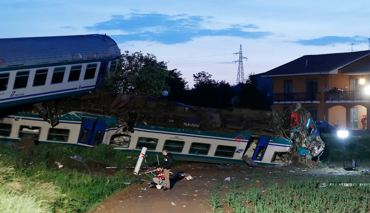 Sebuah rangkaian kereta api mengalami kecelakaan dan keluar jalur di dekat Turin, utara Italia, Kamis (24/5). Regu penyelamat terus mencari kemungkinan adanya penumpang yang terperangkap di puing-puing akibat tabrakan. (AP/Antonio Calanni)
