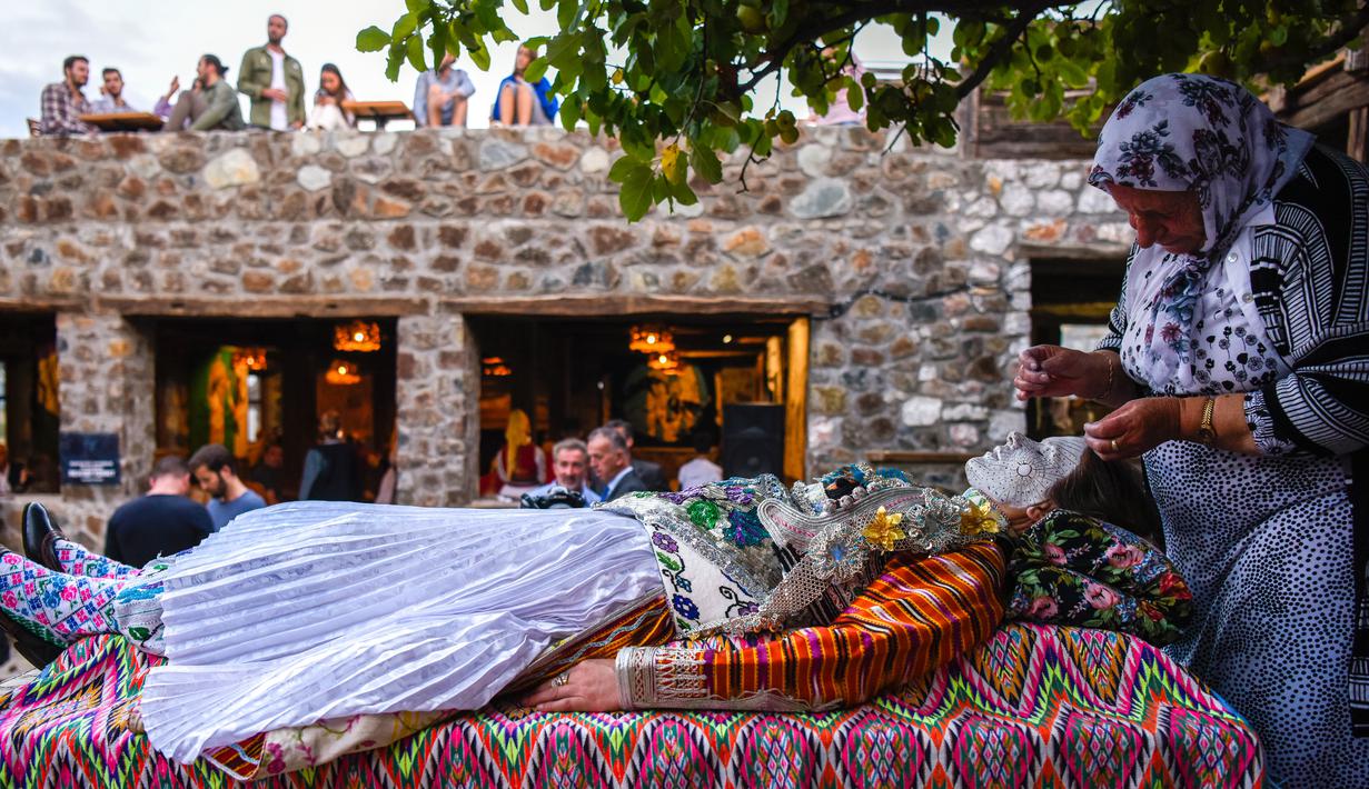 Wanita Kosovo, Sheqerie Buqaj menerima lukisan wajah tradisional oleh Aziza Sefitagic di Desa Kukaj, Kosovo, Rabu (5/9). Sayangnya, kini tradisi melukis wajah bagi pengantin wanita ini sudah di ambang kepunahan. (ARMEND NIMANI/AFP)