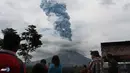 Warga menyaksikan gumpalan asap yang membumbung tinggi ke langit saat Gunung Sinabung memuntahkan uapnya. (AFP/Stringer/wwn)