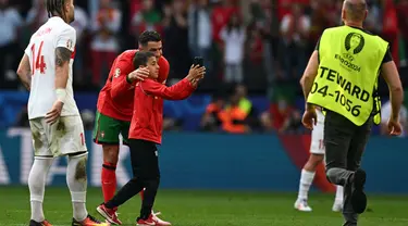 Penyerang Portugal, Cristiano Ronaldo berpose bersama seorang penyerbu lapangan muda selama pertandingan sepak bola Euro 2024 Grup F antara Turki dan Portugal di BVB Stadion, Dortmund pada 22 Juni 2024. (PATRICIA DE MELO MOREIRA/AFP)