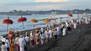 Prosesi ini berlangsung khidmat sebagai upaya penyucian simbol-simbol suci sebelum Nyepi. Tampak dalam foto, umat Hindu saat mengikuti upacara doa Melasti di salah satu pantai di Denpasar, Bali, pada Senin 16 Maret 2026. (SONNY TUMBELAKA/AFP)