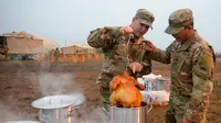 Tentara AS memasak kalkun untuk merayakan Thanksgiving di perbatasan Donna, Texas, Kamis (22/11). Para tentara sedang ditugaskan dalam Operasi Patriot Setia. (Senior Airman Alexandra Minor/U.S. Air Force/Department of Defense via AP)