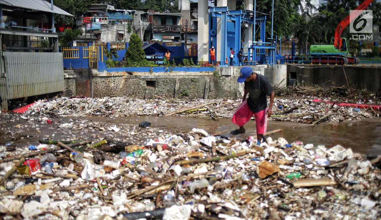 Petugas membersihkan sampah yang menyumbat Pintu Air Manggarai, Jakarta, Selasa (26/2). Meningkatnya debit air Sungai Ciliwung menyebabkan terjadi penumpukan sampah di Pintu Air Manggarai. (Liputan6.com/Faizal Fanani)