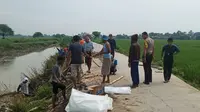 Warga bersama polisi memperbaiki tanggul yang jebol pasca diterjang banjir. (Liputan6.com/Bam Sinulingga)