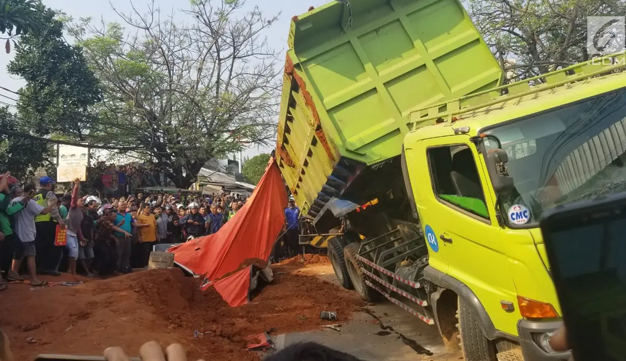 Warga berkerumun menyaksikan proses evakuasi bangkai mobil kecelakaan maut yang hancur tertindih badan truk muatan tanah di Karawaci, Tangerang, Kamis (1/8/2019). Sopir truk yang menimpa mobil dan menewaskan 4 orang itu kabur setelah kecelakaan maut terjadi. (Liputan6.com/Pramita Tristiawati)
