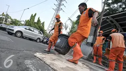 Petugas memindahkan pot saat akan menambal jalan berlubang di wilayah Pasar Senen, Jakarta, Selasa (26/7). Penambalan jalan berlubang ini bertujuan untuk kenyamanan pengguna jalan yang melintas. (Liputan6.com/Yoppy Renato)