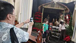 Pengunjung berfoto didekat diorama kelahiran Yesus Kristus di Gereja Katedral, Jakarta (23/12). Jelang perayaan Natal, Gereja Katedral mulai berhias dengan berbagai ornamen, salah satunya diorama kelahiran Yesus Kristus. (Liputan6.com/Immanuel Antonius)