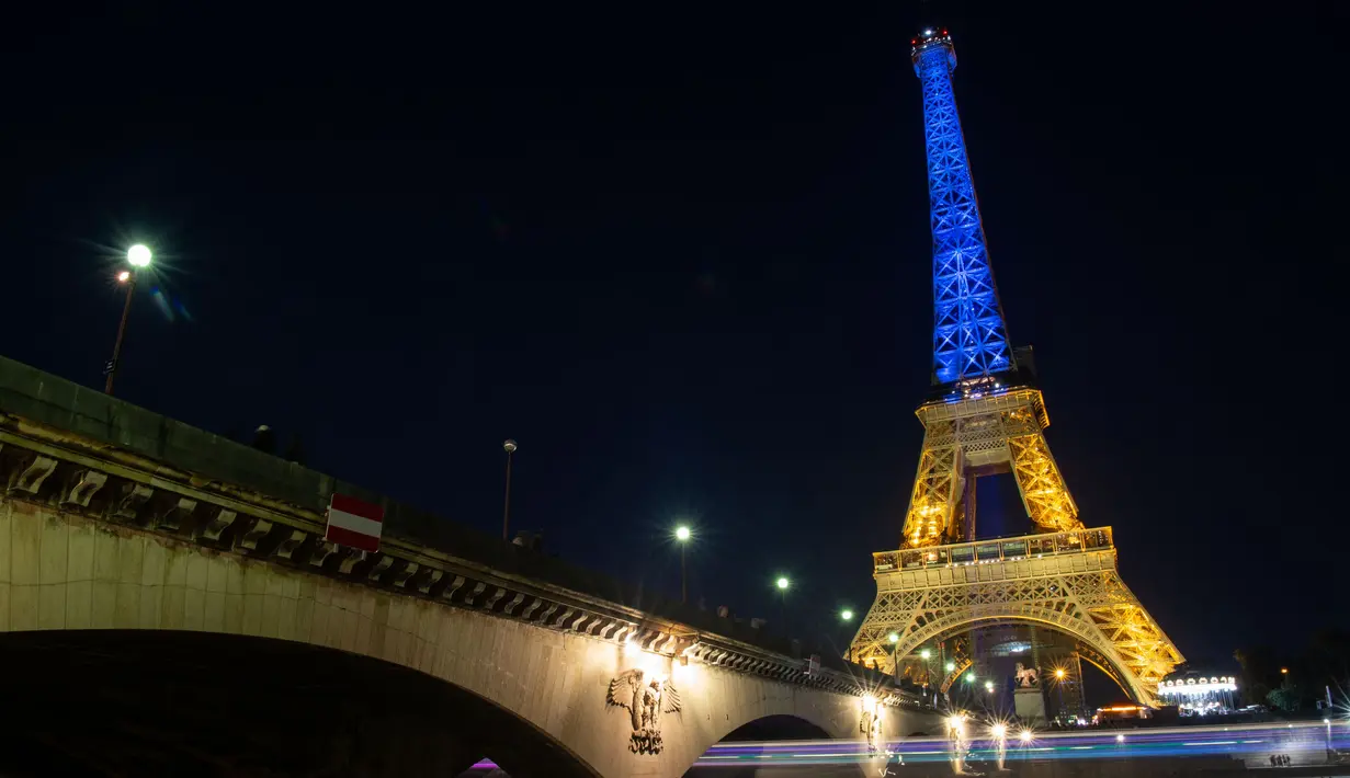 <p>Sebuah foto menunjukkan Menara Eiffel di Paris diterangi dengan warna bendera nasional Ukraina, pada 9 Mei 2022. Memperingati Hari Eropa, Menara Eiffel memproyeksikan bendera Ukraina sebagai solidaritas untuk rakyat Ukraina di tengah invasi Rusia. (AFP)</p>