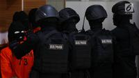 Polisi bersenjata lengkap mengawal sejumlah terduga teroris untuk dihadirkan dalam jumpa pers di Mabes Polri, Jakarta, Jumat (17/5/2019). Sepanjang bulan Mei 2019, tim Densus 88 Antiteror telah menangkap sebanyak 29 terduga teroris jaringan Jamaah Ansharut Daulah (JAD). (Liputan6.com/Johan Tallo)