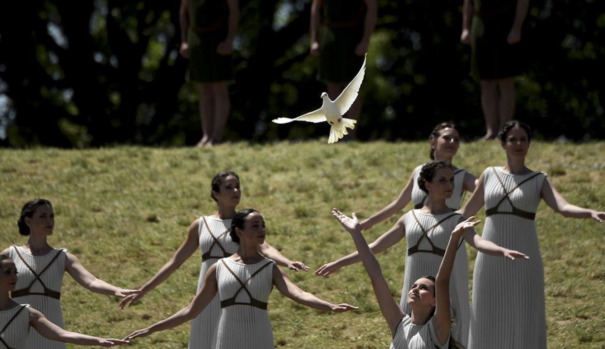 Para aktris menari dan melepaskan burung merpati saat upacara penyalaan api olimpiade di Candi Hera yang terletak di bekas kota tua Olympia, Yunani, Kamis (21/4/2016). (AFP/Aris Messinis)