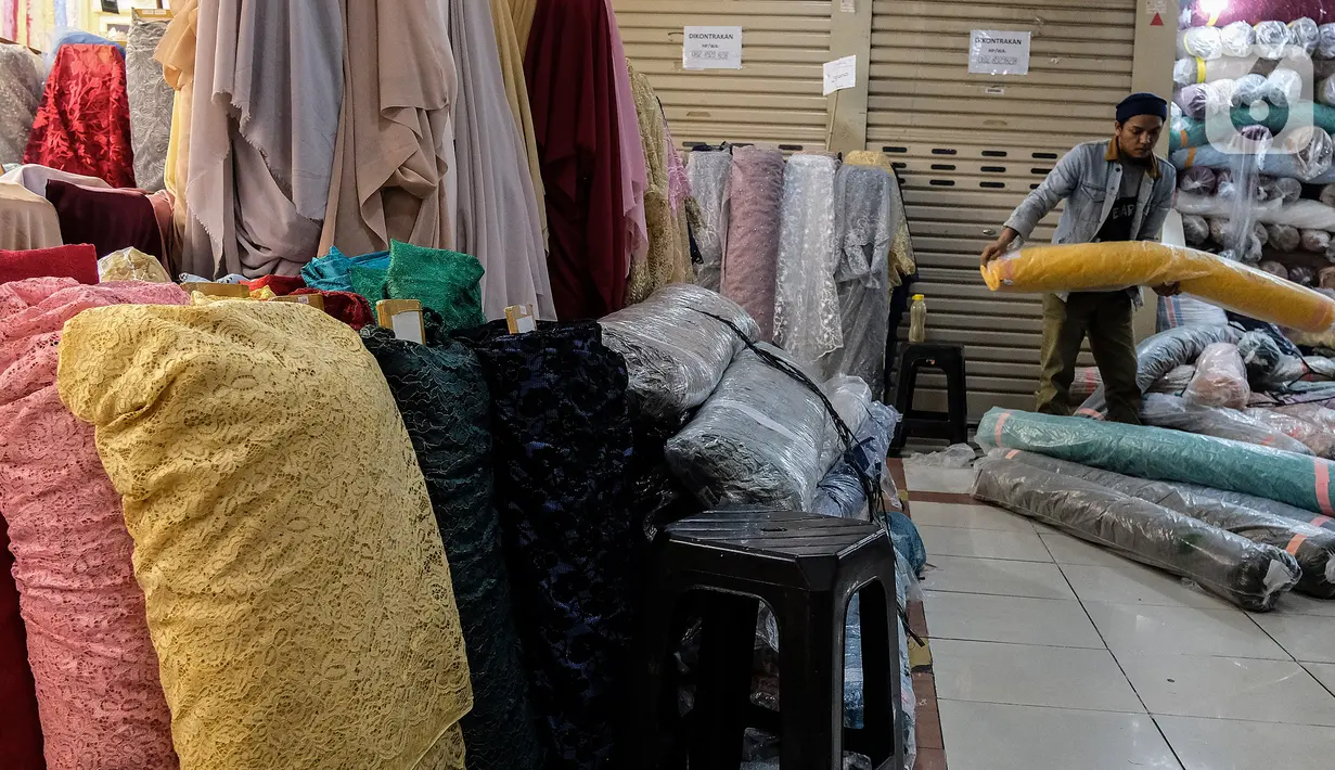 Pekerja menata bahan kain dagangan di Pasar Tanah Abang, Jakarta, Kamis (1/4/2021).  Kementerian Perindustrian mendorong pengembangan bahan baku tekstil yang berbasis serat sintetis untuk mengurangi ketergantungan terhadap bahan baku tekstil impor. (Liputan6.com/Johan Tallo)