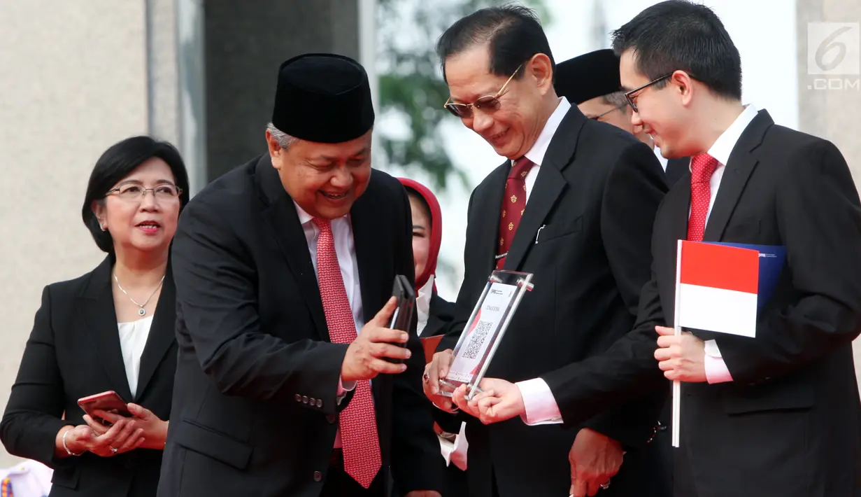 Gubernur BI Perry Warjiyo dan Presdir BCA Jahja Setiaatmadja mencoba transaksi menggunakan QR Code Indonesian Standard (QRIS) di kantor BI, Jakarta, Sabtu (17/8/2019). QRIS merupakan bagian transformasi digital di Sistem Pembayaran Indonesia yang berlaku 1 Januari 2020. (Liputan6.com/HO/Rizal)