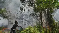 Seorang pria berupaya memadamkan api yang membakar lahan gambut, di Jalan Perdana, Pontianak, Kalbar. (Antara)