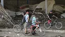 Pria dengan sepeda mereka melihat mobil yang rusak dari sebuah perusahaan perakitan kendaraan setelah tanah longsor saat hujan lebat di Las Tejerias, negara bagian Aragua, Venezuela, pada 10 Oktober 2022. Tanah longsor di Venezuela tengah menyebabkan sedikitnya 22 orang tewas dan lebih dari 50 hilang setelah hujan lebat menyebabkan sungai meluap, kata Wakil Presiden Delcy Rodriguez. (AFP/Yuri Cortez)