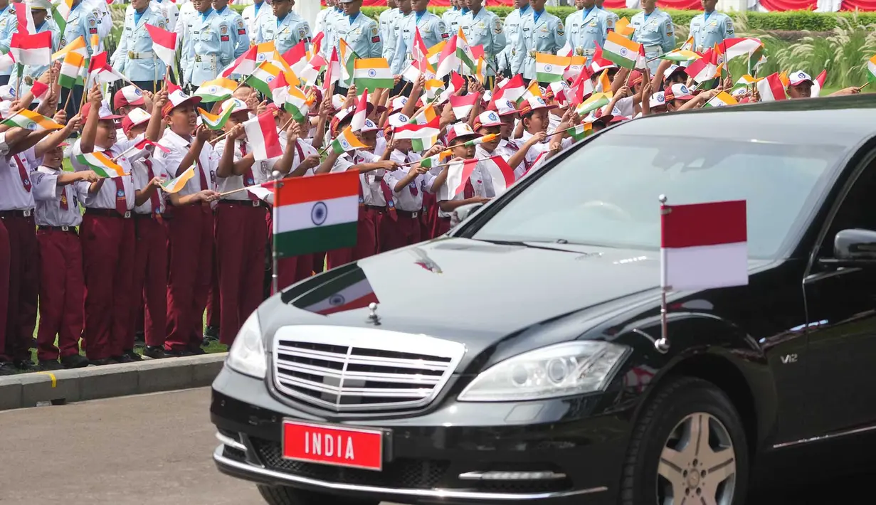 Anak-anak sekolah melambaikan bendera nasional Indonesia dan India saat iring-iringan kendaraan yang membawa Perdana Menteri India Narendra Modi melintas selama upacara penyambutan menjelang pertemuan Modi dengan Presiden Prabowo Subianto di Istana Merdeka di Jakarta,  Selasa, 7 Juli 2026. (AP Photo/Achmad Ibrahim)
