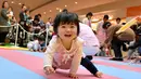 Seorang bayi tersenyum dan ingin menghampiri ibunya saat kompetisi 'Bayi Merangkak',  Yokohama, Jepang, Senin (23/11/2015). Tingkah bayi yang lucu menjadi pemandangan yang menggemaskan bagi para penonton. (AFP Photo/Kazuhiro Nogi)