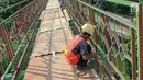 Pekerja menyelesaikan pembangunan jembatan gantung yang diberi julukan Indiana Jones di Srengseng Sawah, Jagakarsa, Jakarta, Jumat (3/8). Pemprov DKI membangun jembatan Indiana Jones karena yang lama sudah tidak layak. (Liputan6.com/Immanuel Antonius)