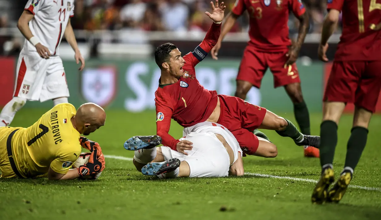Bintang timnas Portugal, Cristiano Ronaldo dilanggar pada laga kedua kualifikasi Piala Eropa 2020 yang berlangsung di Stadion Da Luz, Lisbon, Senin (27/3). Portugal raih hasil imbang 1-1 kontra Serbia. (AFP/Patricia de Melo)