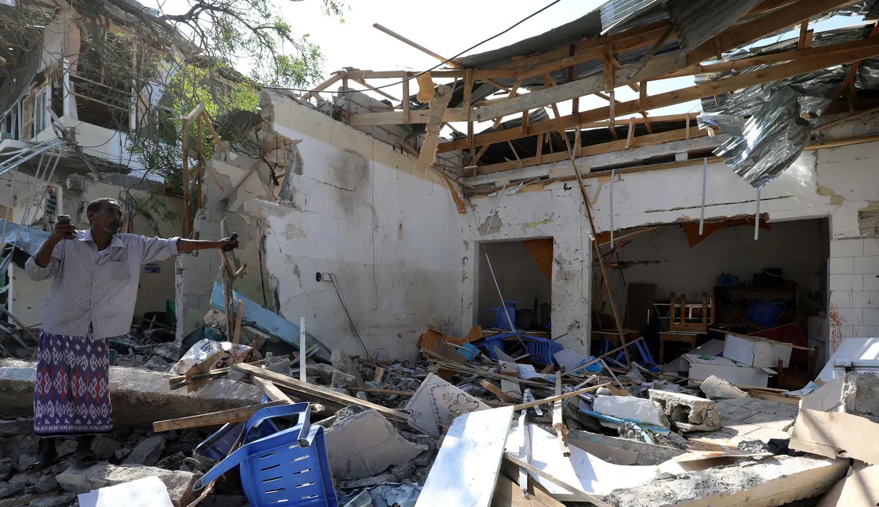 Seorang pria berdiri di tengah reruntuhan bangunan yang hancur akibat ledakan bom mobil di Mogadishu, Somalia (28/3). Insiden tersebut telah menyebabkan 11 orang tewas dan belasan lainnya terluka. (Reuters/Feisal Omar)
