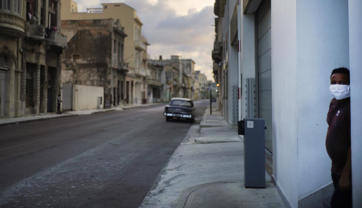 Seorang pria yang mengenakan masker berdiri di samping jalanan kosong saat penerapan jam malam di Havana, Kuba, Selasa (1/9/2020). Otoritas Kuba menerapkan lockdown selama 15 hari di Havana untuk keluar dari penularan COVID-19 tingkat rendah tetapi terus-menerus. (AP Photo/Ramon Espinosa)