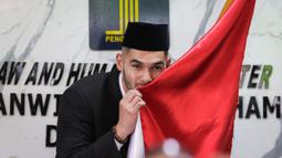 Sandy Walsh mencium bendera Merah Putih di depan wartawan usai pengambilan sumpah janji setia pewarganegaraan Jordi Amat dan Sandy Walsh di Kantor Wilayah Kemenkumham DKI Jakarta, Cawang, Jakarta, Kamis (17/11/2022). (Bola.com/Bagaskara Lazuardi)