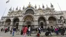 Wisatawan berjalan melintasi Lapangan Santo Markus dengan latar Basilika Santo Markus di Venesia (4/11/2019). Basilika Santo Markus adalah gereja di Venesia paling terkenal dan salah satu contoh yang paling terkenal dari arsitektur Bizantium. (AFP Photo/Miguel Medina)