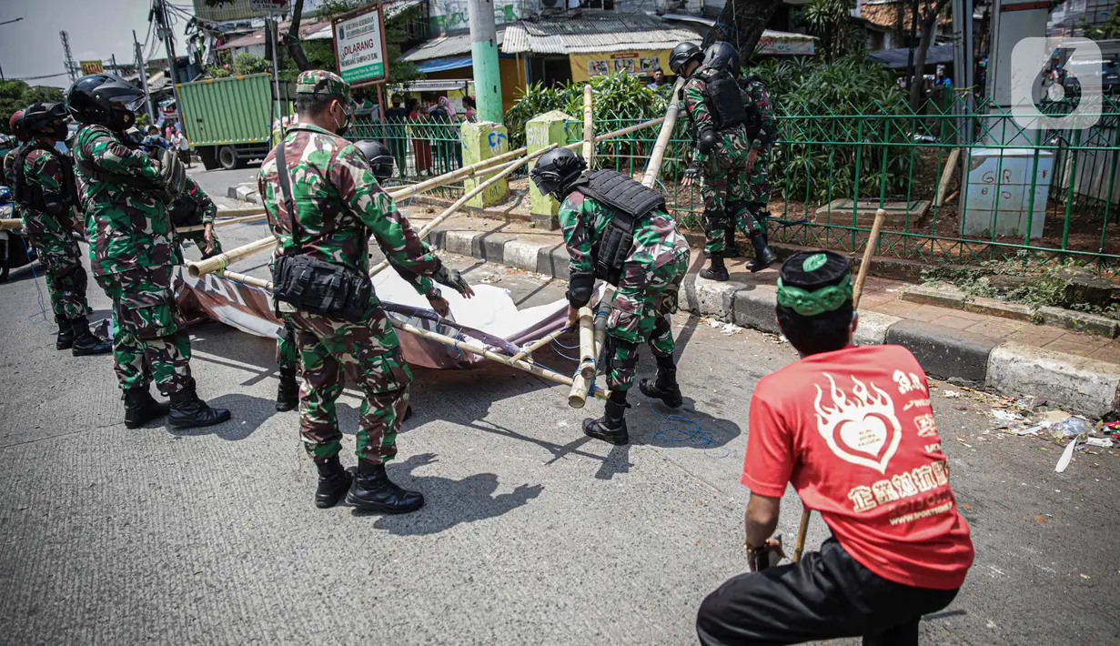 Seorang warga meminta anggota TNI untuk tidak mencopot paksa baliho Rizieq Shihab yang terpasang di sekitar kawasan Petamburan, Jakarta, Jumat (20/11/2020). Pencopotan dilakukan karena menyalahi aturan yang telah ditetapkan. (Liputan6.com/Faizal Fanani)