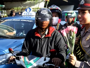 Sejumlah Polisi Wanita (Polwan) membagikan bunga kepada pengendara yang melintas di perempatan Slipi, Jakarta, Selasa (21/4/2015). Pembagian bunga ini dalam rangka memperingati hari Kartini.(Liputan6.com/Johan Tallo)