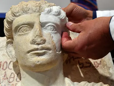 Peneliti memasangkan bagian wajah yang hilang dari sebuah patung yang berumur sekitar 2-3 abad di Roma, Kamis (16/2). Patung tersebut hancur akibat dari serangan ISIS. (AFP PHOTO / Alberto PIZZOLI)