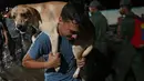 Seorang pria membawa anjingnya setelah tanah longsor akibat hujan lebat di El Castaño, Venezuela, Senin (17/10/2022). Petugas penyelamat terus berupaya membersihkan gundukan puing-puing di kota Las Tejerías yang dilanda bencana tanah longsor.  (Federico Parra / AFP)