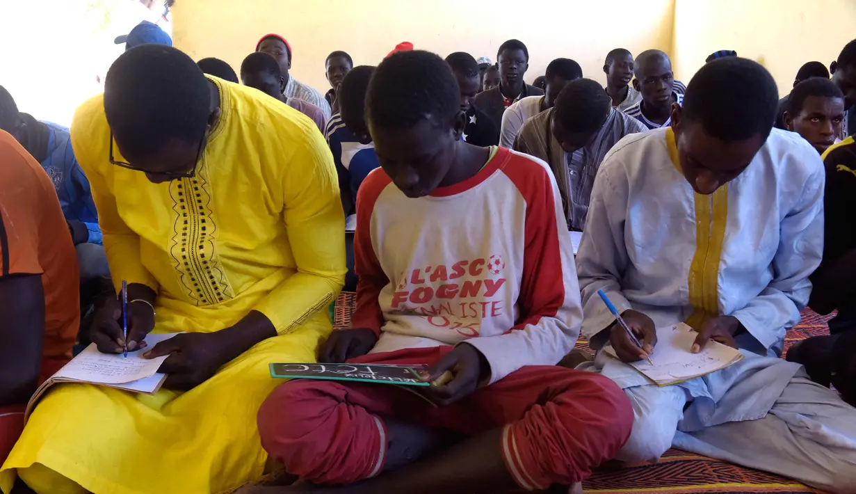 Murid menulis di buku saat menghadiri kelas di sekolah dasar di Pikine, Dakar, (30/1). Pendidikan di Senegal menjadi prioritas saat konferensi ketiga tentang pemulihan dana Kemitraan Global untuk Pendidikan (GPE) mulai 1 Februari 2018. (AFP Photo/Seyllou)