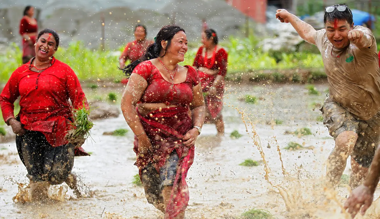 Warga Nepal bersuka ria sambil menari di lumpur pada Asar Pandra, atau hari menanam padi nasional di Lalitpur, 29 Juni 2018. Asar Pandra diadakan sebagai tanda dimulainya kembali aktivitas tanam padi di sawah saat musim hujan tiba. (AP Photo/Niranjan Shre