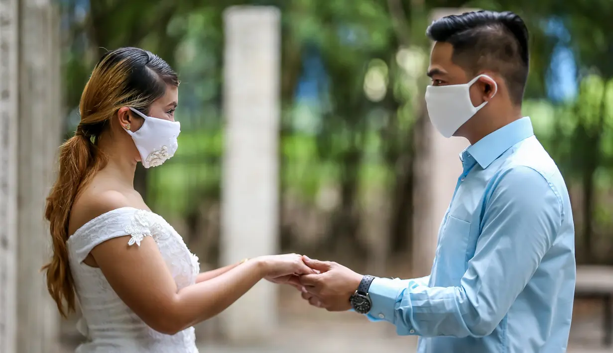 Pasangan berpegangan tangan dalam "pernikahan massal bermasker" di sebuah taman di Kota Makati, Filipina (15/12/2020). Pemerintah Filipina telah memberlakukan kebijakan untuk penggunaan masker di tengah kekhawatiran lonjakan kasus COVID-19 selama musim liburan. (Xinhua/Rouelle Umali)
