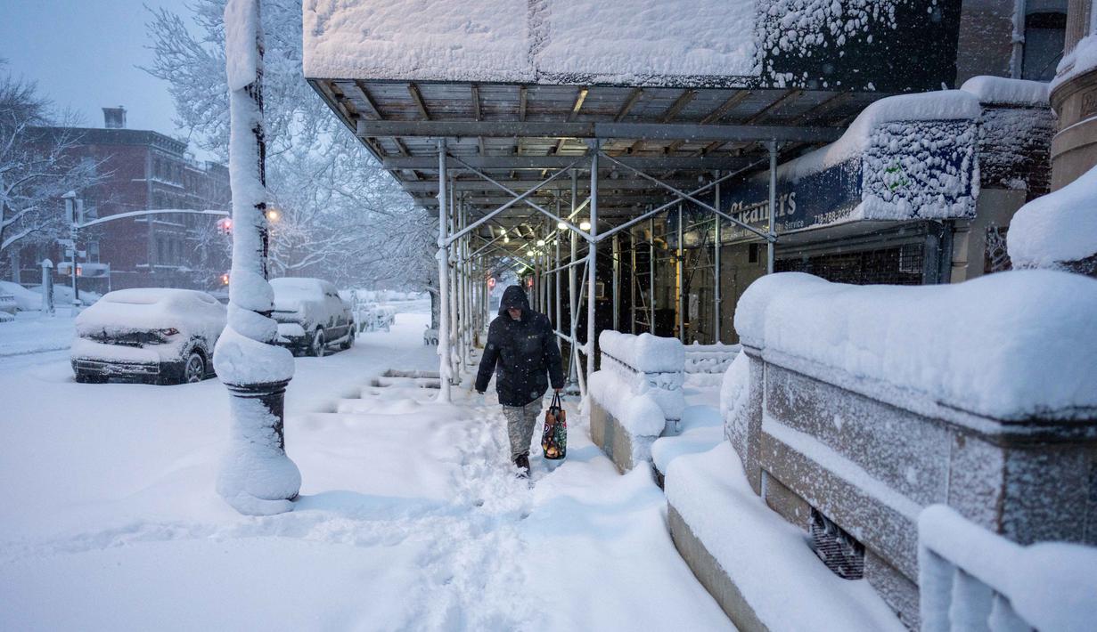 Wali Kota New York, Zohran Mamdani, mengatakan kota itu diperkirakan menerima 45 hingga 55 sentimeter salju dengan hembusan angin hingga 80 kilometer per jam serta potensi banjir pesisir hingga 75 sentimeter saat pasang tertinggi. Tampak dalam foto, seseorang berjalan susah payah menembus salju beberapa menit setelah matahari terbit di distrik Brooklyn, Kota New York, pada Senin 23 Februari 2026. (Jeremy Weine/Getty Images North America/Getty Images via AFP)
