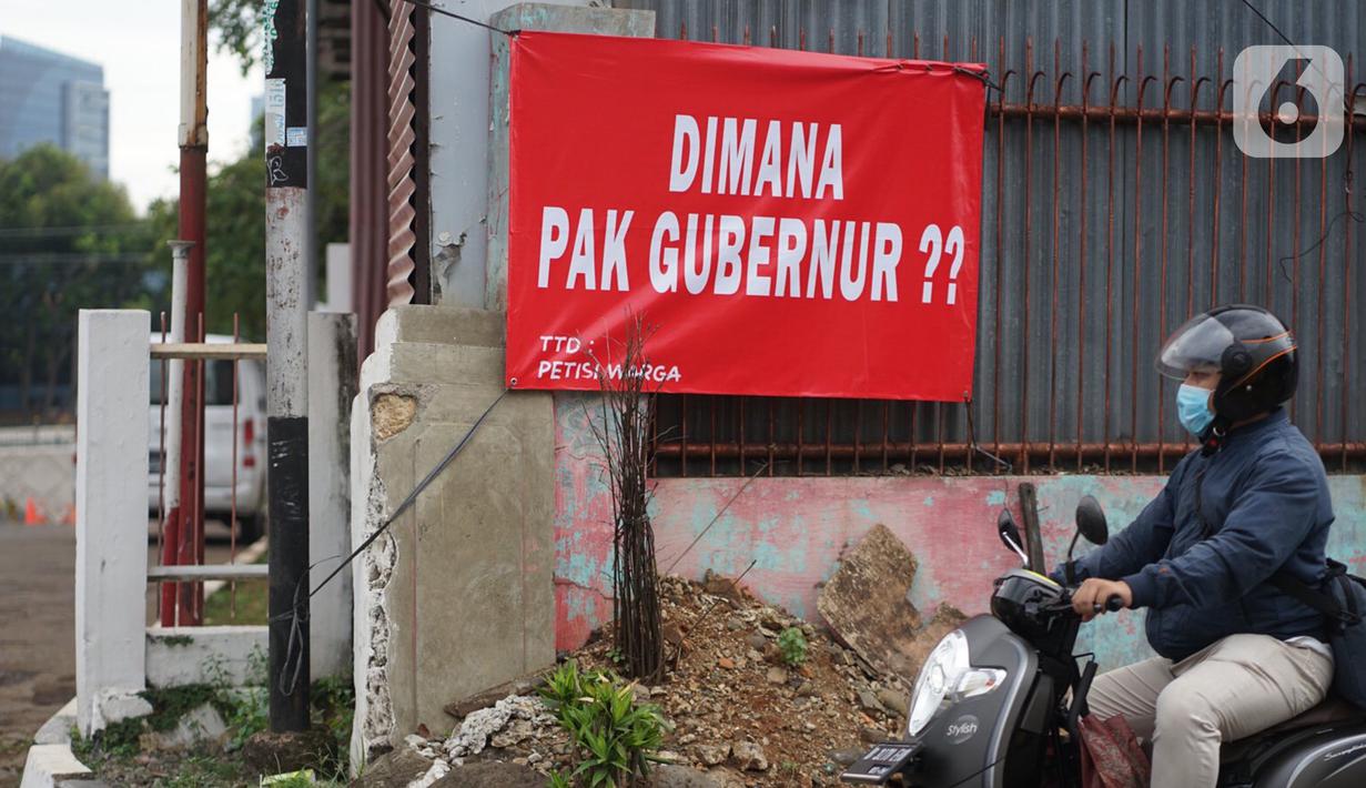 Pengguna jalan melintas di depan poster protes warga terhadap pembangunan flyover di kawasan Tanjung Barat, Jakarta, Rabu (15/7/2020). Dalam poster protes tersebut, warga menuntut agar pembayaran pelunasan pembebasan lahan segera diselesaikan secara serentak. (Liputan6.com/Immanuel Antonius)