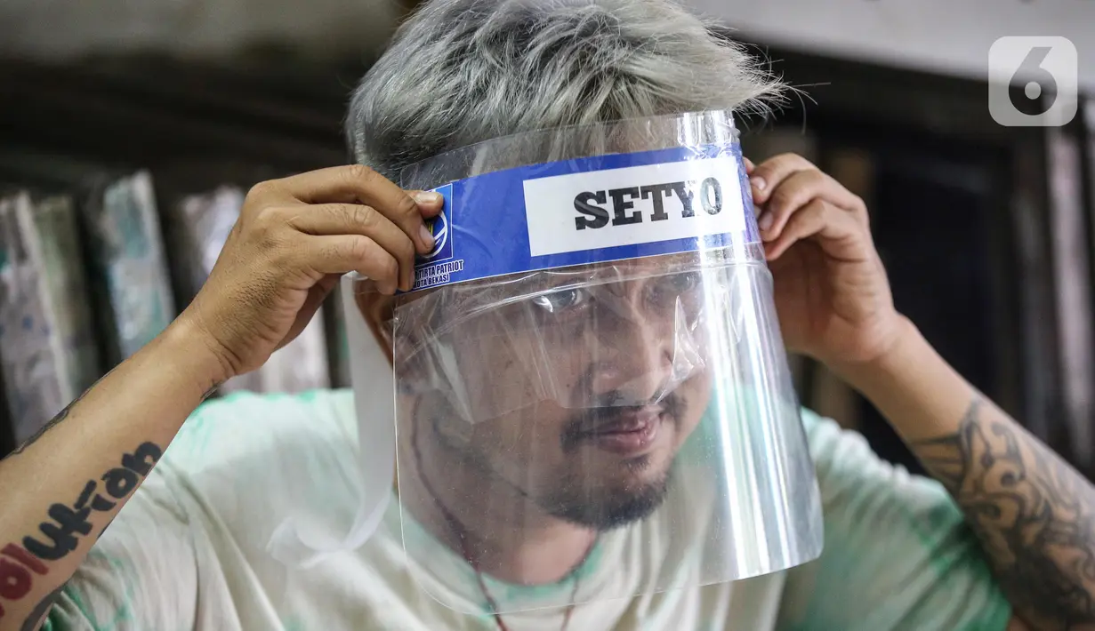 Bucek mengenakan face shield di workshopnya di kawasan Bekasi, Jawa Barat, Rabu (3/6/2020). Pemerintah mewajibkan petugas pelayanan, pedagang, serta pekerja toko swalayan dan mal mengenakan face shield saat fase new normal diterapkan. (Liputan6.com/Faizal Fanani)