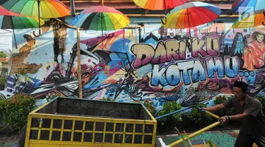 Warga melintasi gambar mural/grafiti di Kampung Bekelir, Jalan Perintis Kemerdekaan, Kota Tangerang, Banten, Selasa (17/4). Kampung Bekelir pada 10 tahun lalu merupakan kawasan yang kumuh. (Merdeka.com/Arie Basuki)