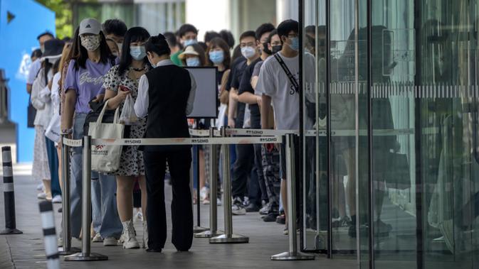 Karyawan yang mengenakan masker menunggu hasil tes COVID-19 mereka diperiksa untuk memasuki gedung perkantoran di kawasan pusat bisnis di Beijing, China, Selasa (31/5/2022). Penguncian COVID-19 di Shanghai telah mencekik ekonomi nasional dan sebagian besar mengurung jutaan orang di rumah mereka. (AP Photo/Mark Schiefelbein)