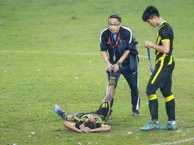 Pemain Timnas Malaysia U-19, Adam Farhan Mohd Faizal (kiri) tengah mendapatkan perawatan dari salah satu official tim saat timnya merayakan juara Piala AFF U-19 2022 di Stadion Patriot Candrabhaga, Bekasi, Jumat (15/07/2022). (Bola.com/Bagaskara Lazuardi)