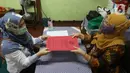 Guru membagikan laporan hasil belajar (rapor) kenaikan kelas kepada wali murid di SD Negeri Menteng 01 Jakarta, Kamis (25/6/2020). Pembagian dilaksanakan mengikuti protokol kesehatan COVID-19 serta membagikan rapor secara bertahap dari 24-26 Juni 2020. (Liputan6.com/Herman Zakharia)