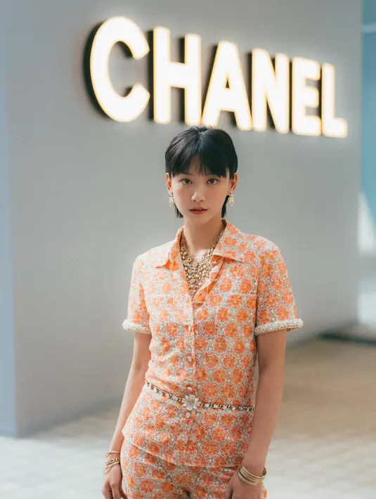 Angela Yuen menyalurkan gaya vintage dengan jumpsuit bermotif yang didominasi warna peach. Penampilannya dipermanis dengan perhiasan dan mini bag Chanel. [Dok/Chanel].